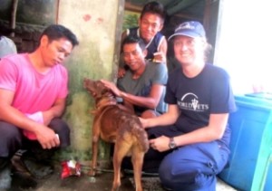 World Vets disaster response member, Dr. Helle Hydeskov, sits with a family in Guiyan, East Samar, after treating a skin infection in their dog
